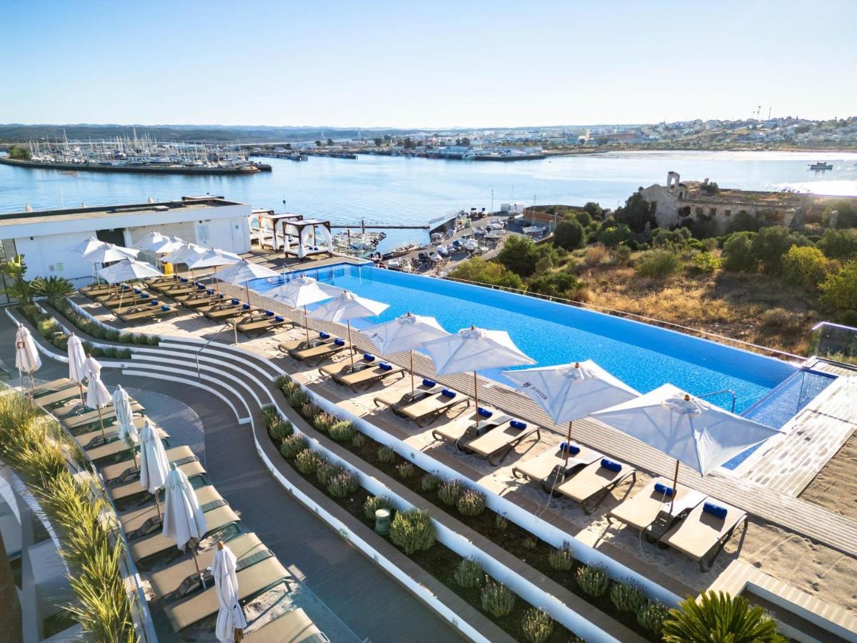 uma imagem de uma piscina num resort com espreguiçadeiras em Jupiter Marina Hotel - Couples & Spa em Portimão
