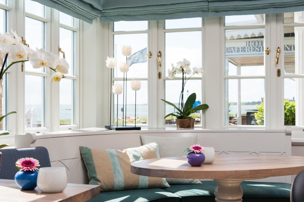 Zimmer mit einem Tisch und einigen Fenstern in der Unterkunft Hotel Fährhaus in Munkmarsch