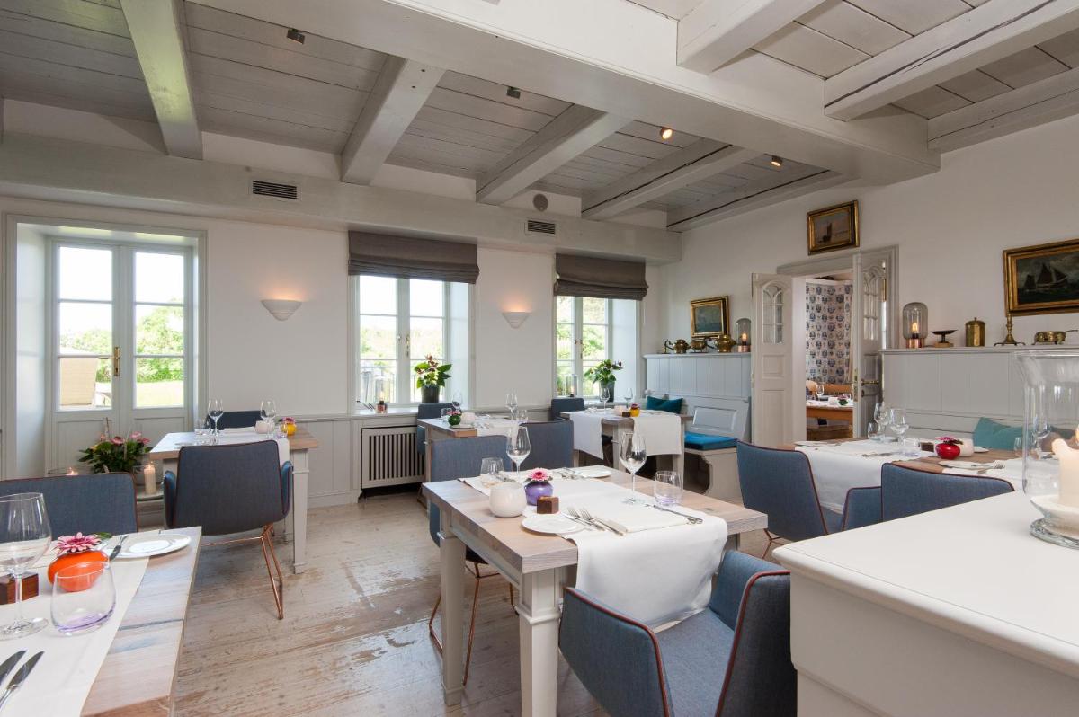 ein Restaurant mit Tischen und Stühlen und Fenstern in der Unterkunft Hotel Fährhaus in Munkmarsch