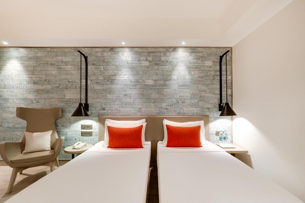 a bedroom with two beds and a chair at Lemon Tree Premier, Mumbai International Airport in Mumbai