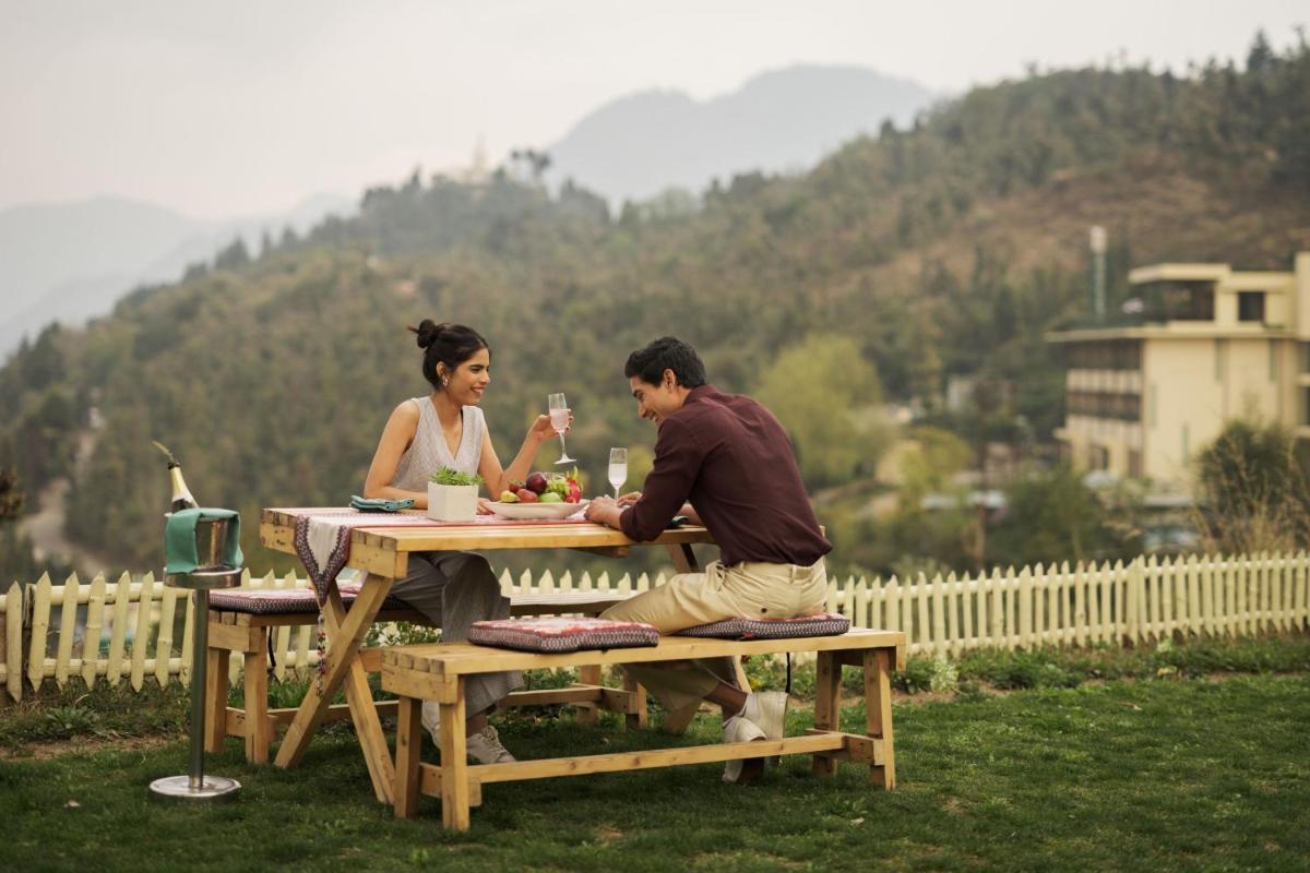 a man and woman sitting at a picnic table at JW Marriott Mussoorie Walnut Grove Resort & Spa in Mussoorie