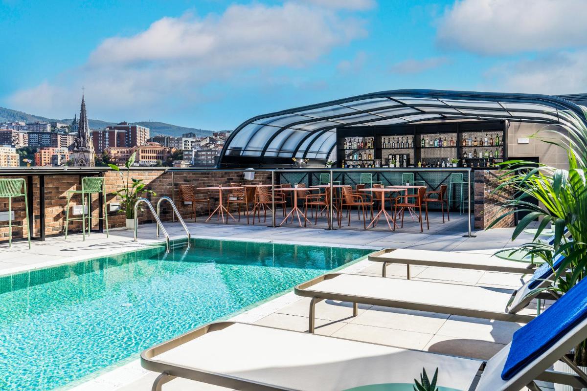 un bar en la azotea con piscina y vistas a la ciudad en Axel Hotel Bilbao - Adults Only, en Bilbao