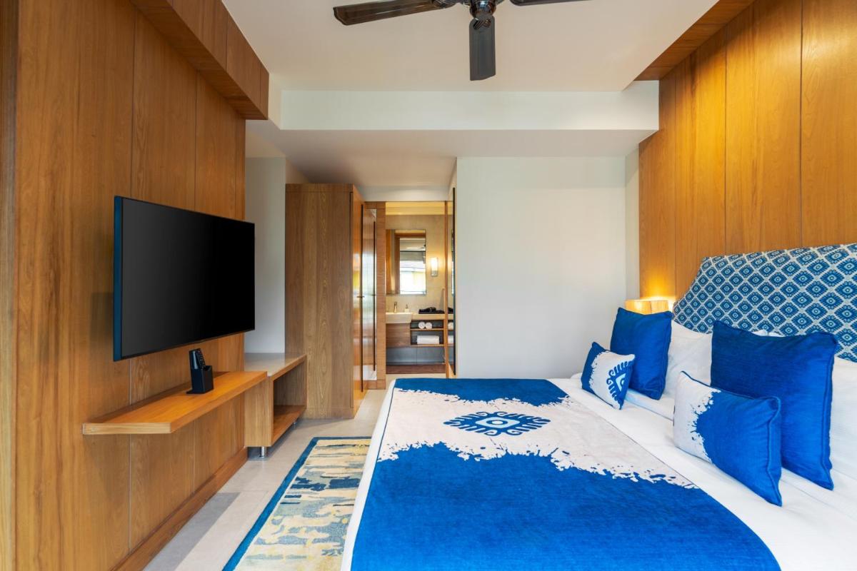 a bedroom with a large bed with a flat screen tv at The Astor - All Suites Hotel Candolim Goa in Candolim a bedroom with a large bed with a flat screen tv at The Astor - All Suites Hotel Candolim Goa in Candolim