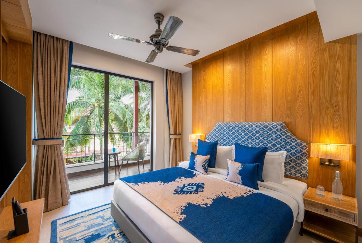 a bedroom with a large bed and a large window at The Astor - All Suites Hotel Candolim Goa in Candolim a bedroom with a large bed and a large window at The Astor - All Suites Hotel Candolim Goa in Candolim
