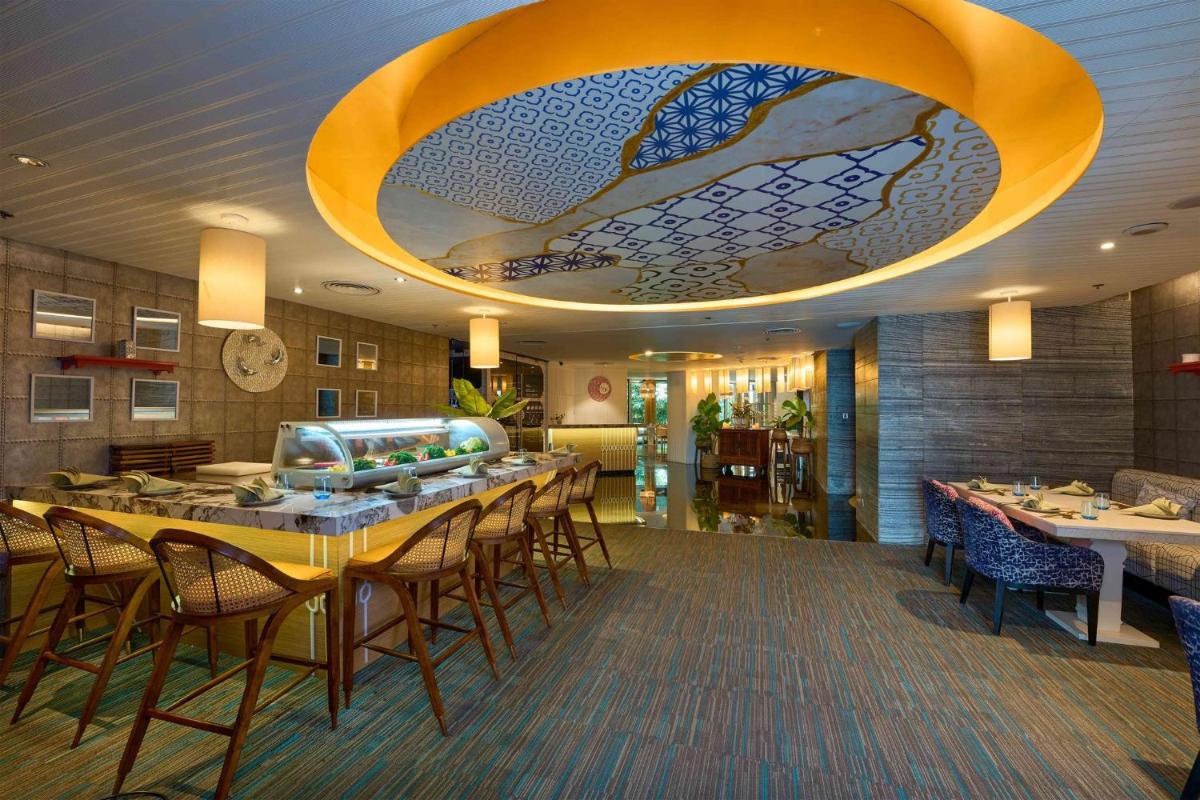a restaurant with tables and chairs and a large ceiling at Crowne Plaza Kochi by IHG in Cochin