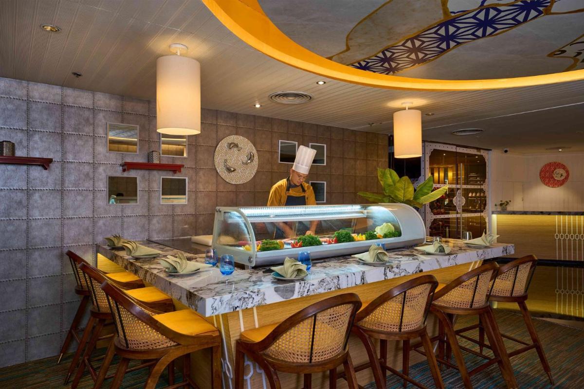 a restaurant with a long table with chairs and a chef at Crowne Plaza Kochi by IHG in Cochin