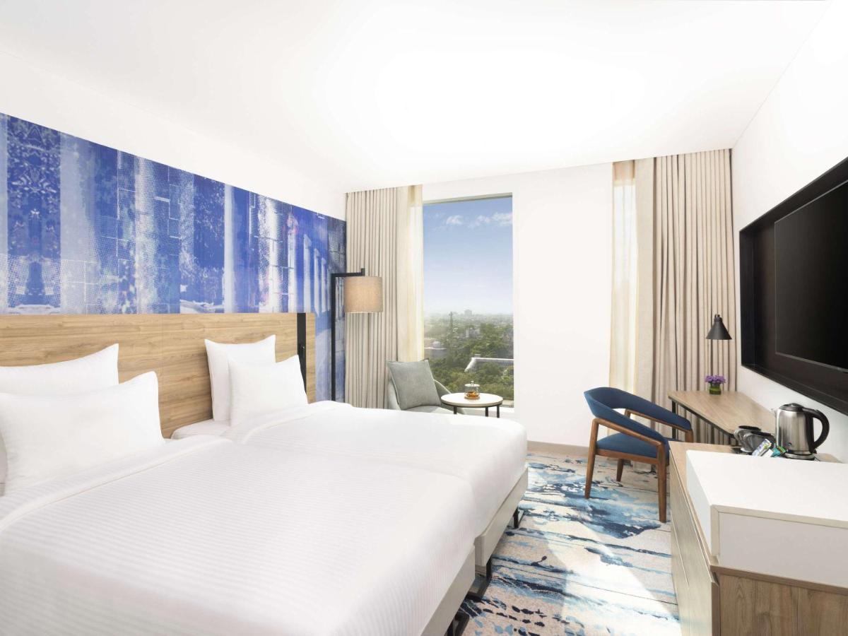 a hotel room with a bed and a television at Novotel New Delhi City Centre in New Delhi a hotel room with a bed and a television at Novotel New Delhi City Centre in New Delhi