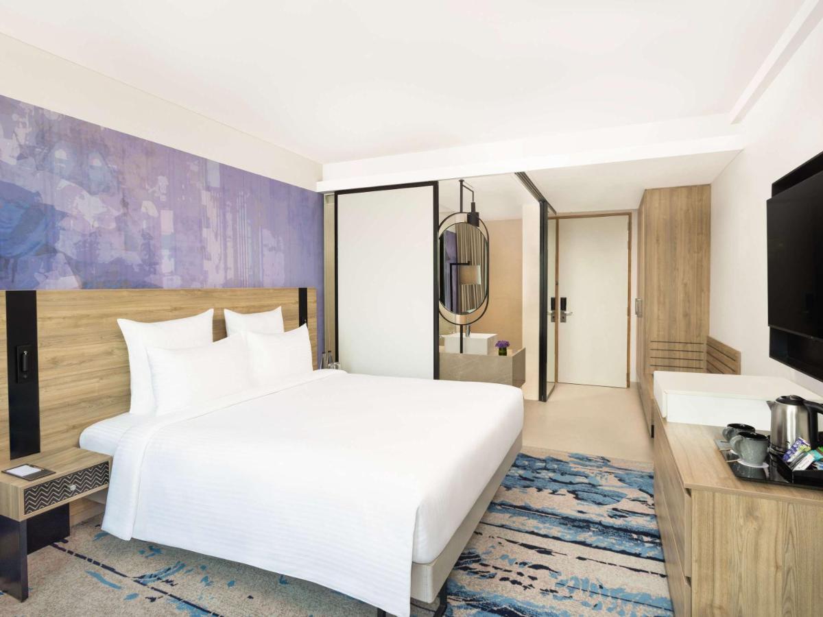 a bedroom with a large white bed and a tv at Novotel New Delhi City Centre in New Delhi a bedroom with a large white bed and a tv at Novotel New Delhi City Centre in New Delhi