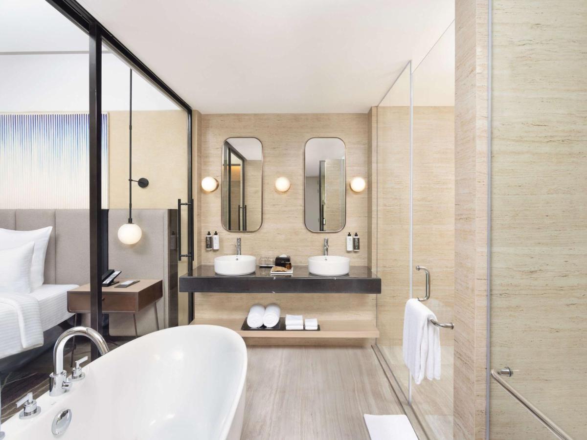 a bathroom with two sinks and two mirrors at Novotel New Delhi City Centre in New Delhi a bathroom with two sinks and two mirrors at Novotel New Delhi City Centre in New Delhi