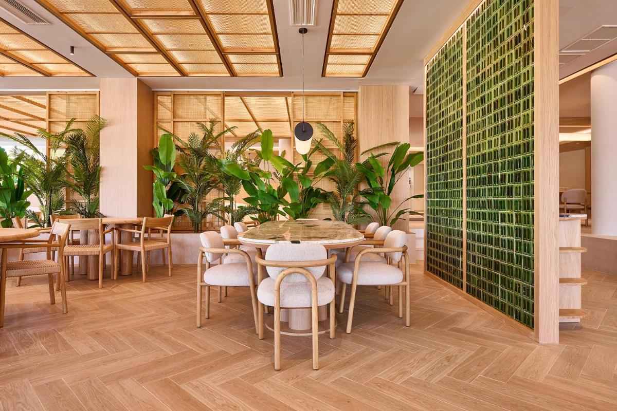 Un comedor con mesas y sillas y plantas. en Calderona Wellness, en Bétera