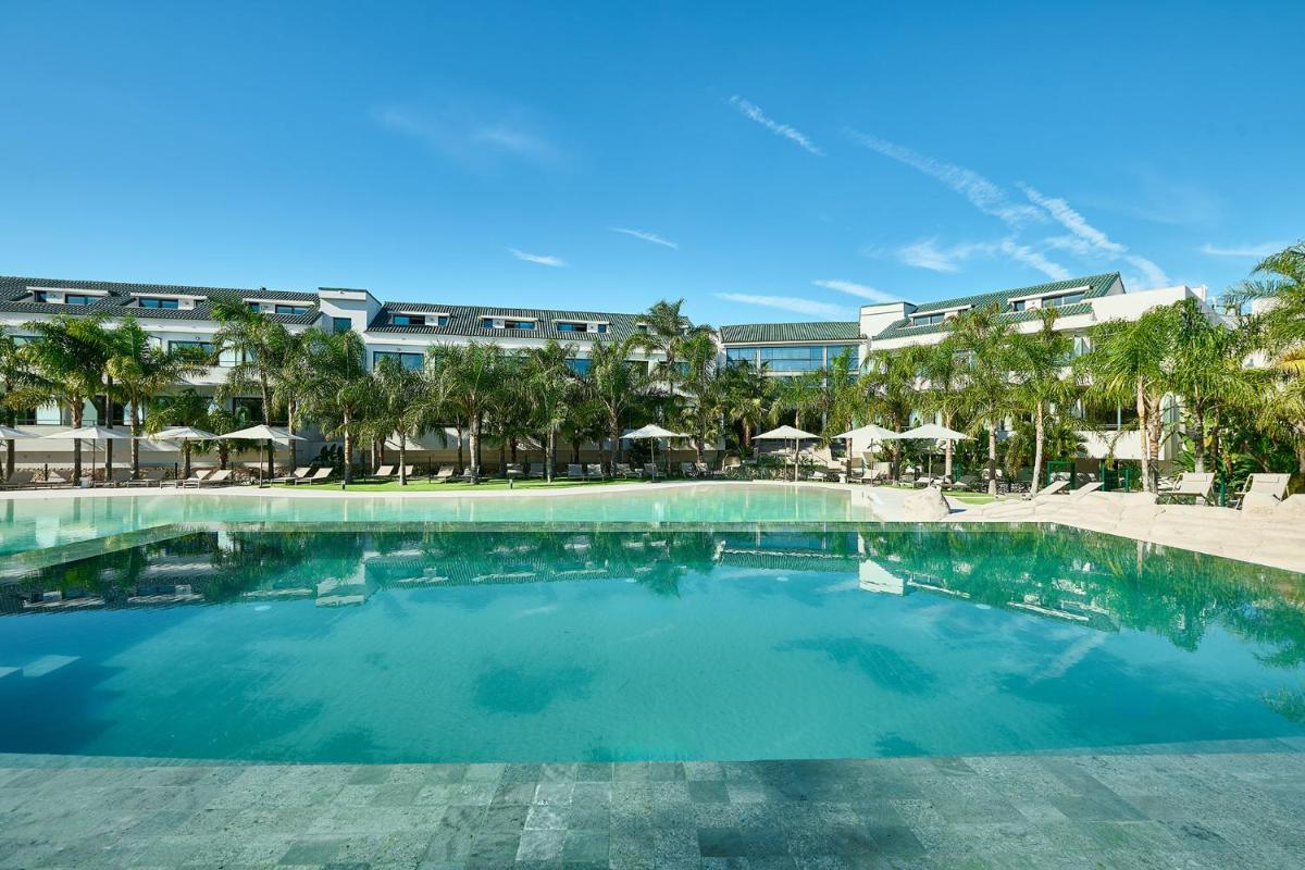 Una gran piscina con palmeras y un edificio. en Calderona Wellness, en Bétera