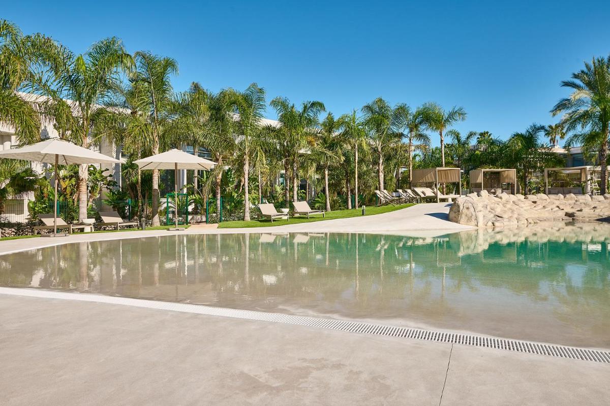 una piscina con sillas y sombrillas en un resort en Calderona Wellness, en Bétera