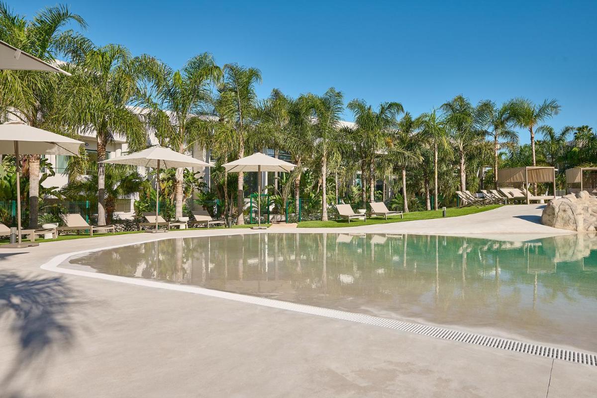 una piscina con sillas y sombrillas en un resort en Calderona Wellness, en Bétera