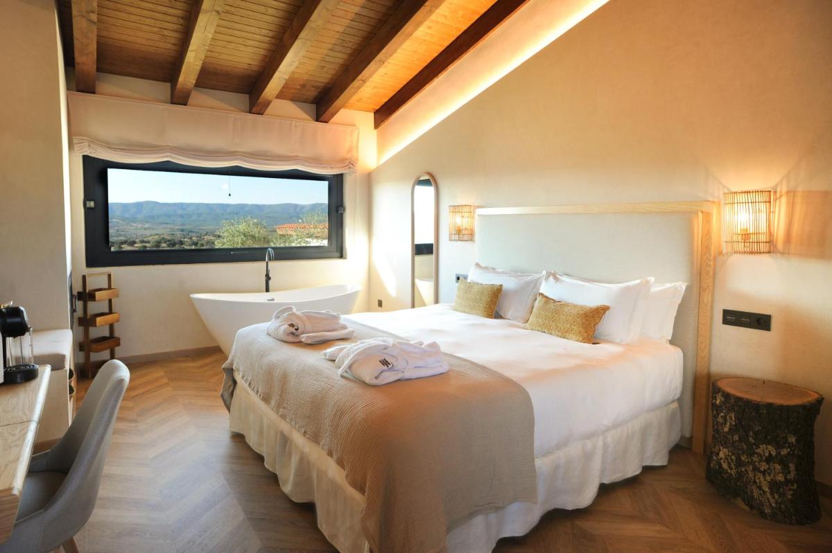 1 dormitorio con 1 cama grande, bañera y ventana en Hábitat Cigüeña Negra, en Valverde del Fresno