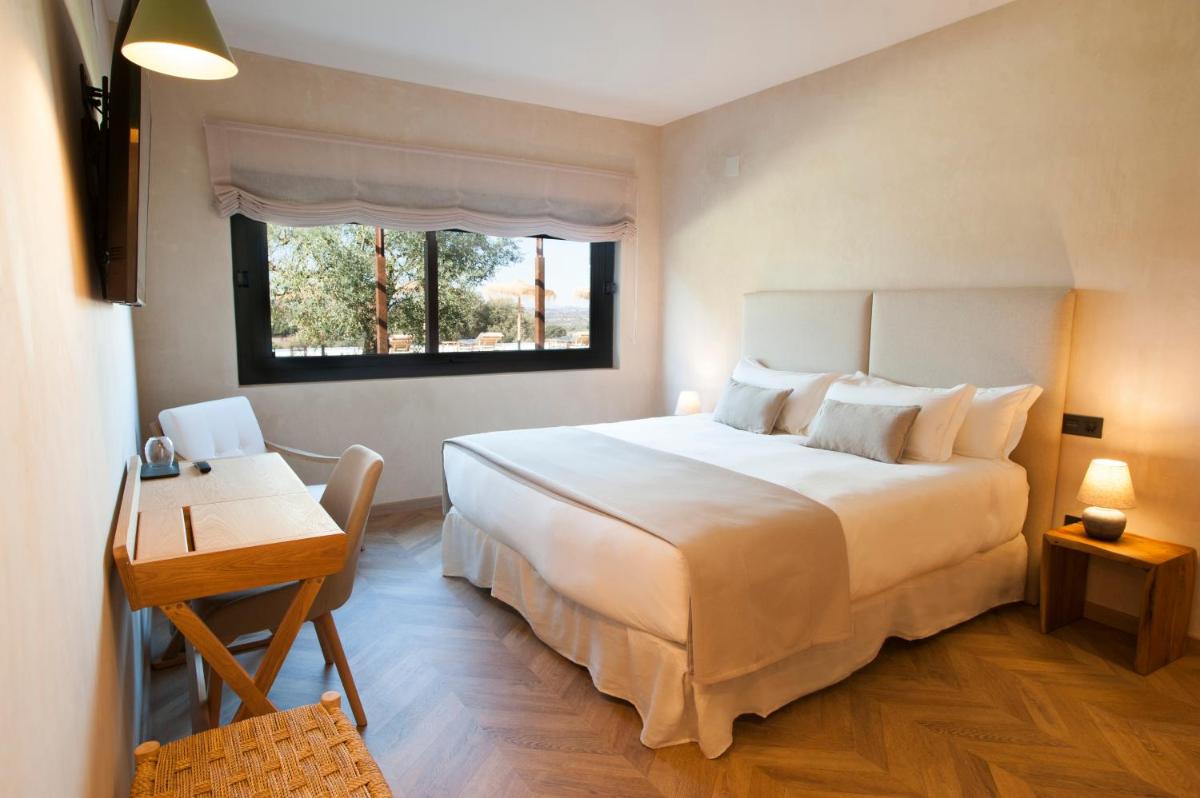 Un dormitorio con una gran cama blanca y un escritorio. en Hábitat Cigüeña Negra, en Valverde del Fresno