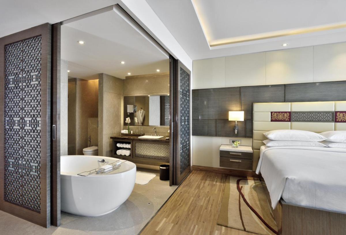 a bedroom with a bed and a bath tub next to a bed at JW Marriott Mumbai Sahar Airport in Mumbai a bedroom with a bed and a bath tub next to a bed at JW Marriott Mumbai Sahar Airport in Mumbai