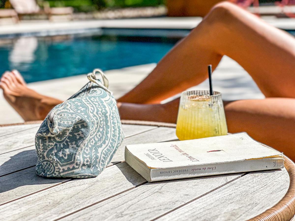 une femme assise sur une table avec un livre et un verre dans l'établissement L'Arcalod & Bistrot Jeanne - Lac d'Annecy - Hôtel Restaurant Spa, à Doussard