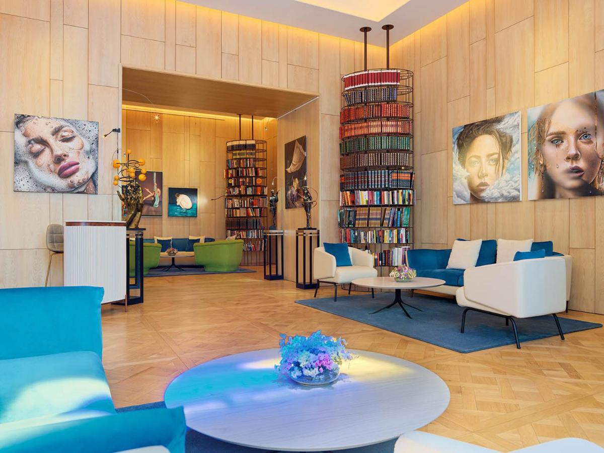 uma biblioteca com sofás, cadeiras, uma mesa e livros em The One Palácio da Anunciada em Lisboa