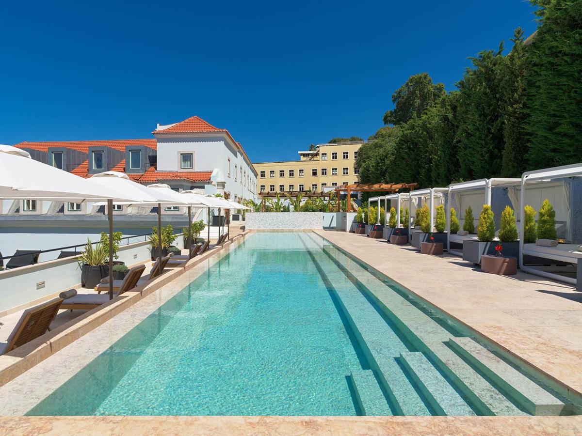 uma piscina com bancos e guarda-sóis num edifício em The One Palácio da Anunciada em Lisboa
