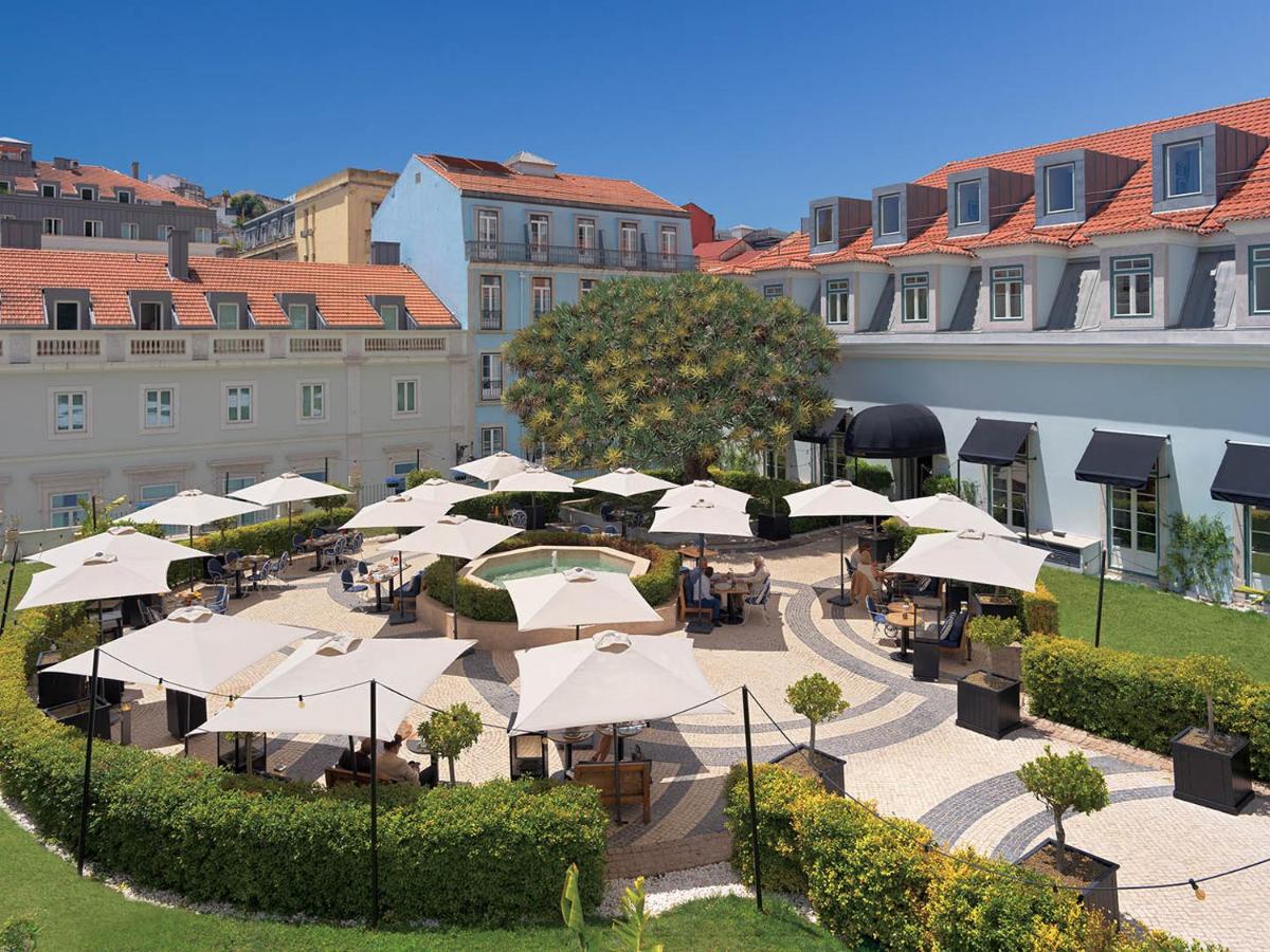 um pátio exterior com mesas e guarda-sóis brancos em The One Palácio da Anunciada em Lisboa