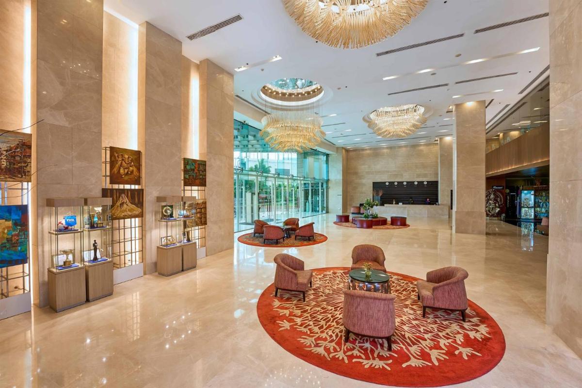 a lobby with chairs and tables and a chandelier at Crowne Plaza Kochi by IHG in Cochin