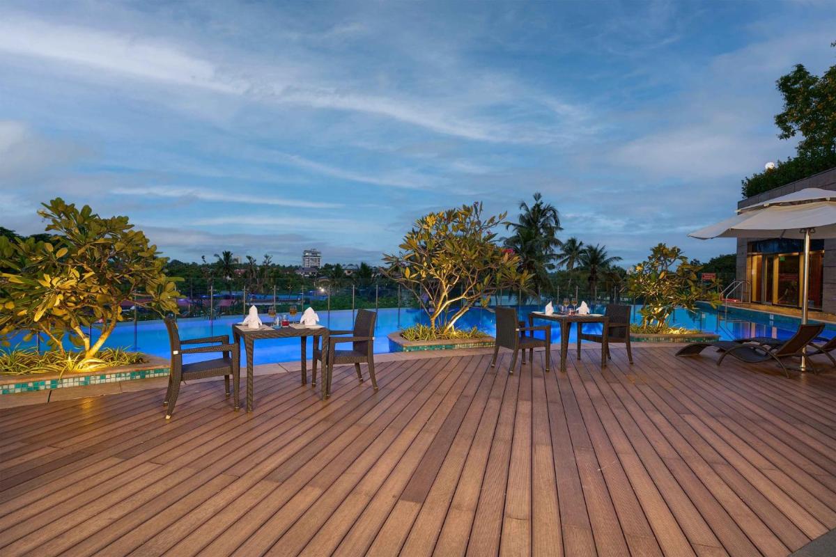 a wooden deck with tables and chairs and a pool at Crowne Plaza Kochi by IHG in Cochin