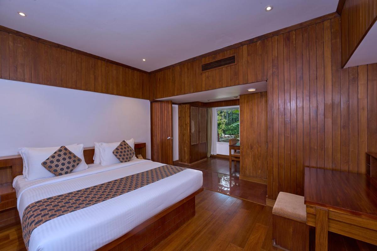a bedroom with a white bed and wooden walls at Casino Hotel - CGH Earth, Cochin in Cochin
