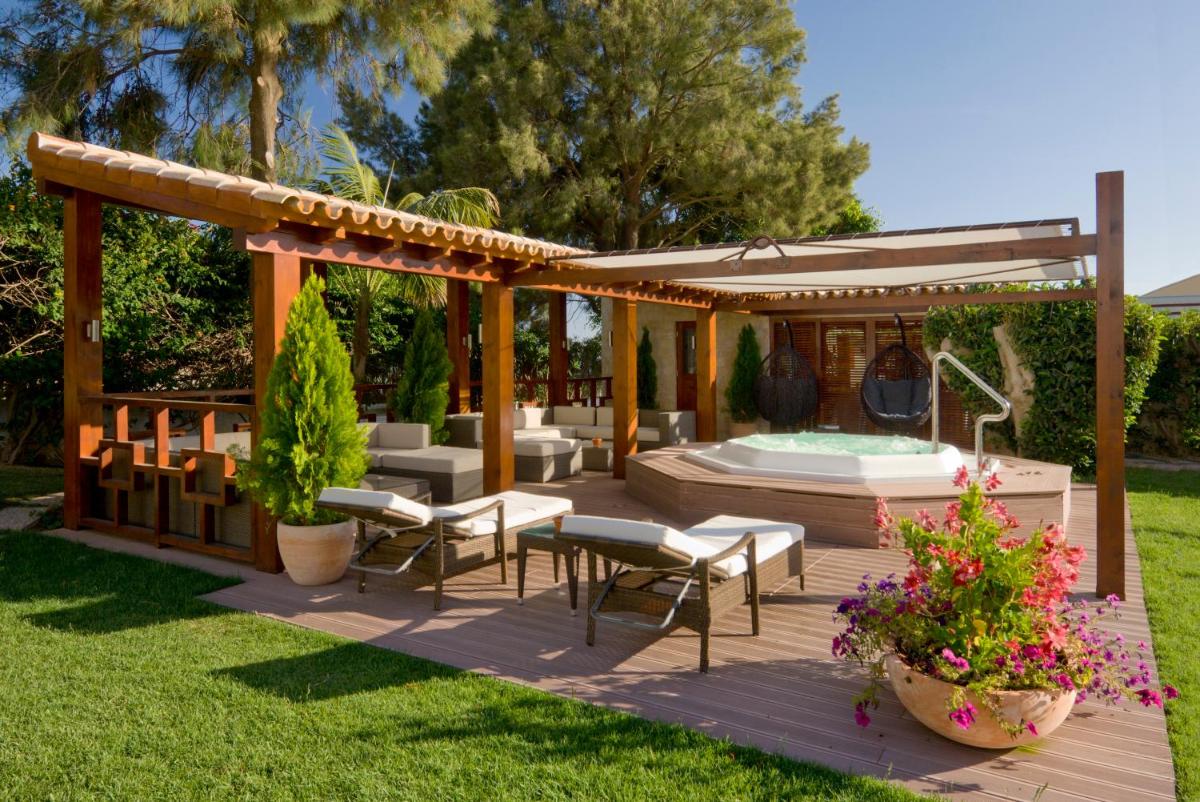 um deque no quintal com uma banheira de hidromassagem e um gazebo em Cerro Da Marina Hotel - Adults Only em Albufeira