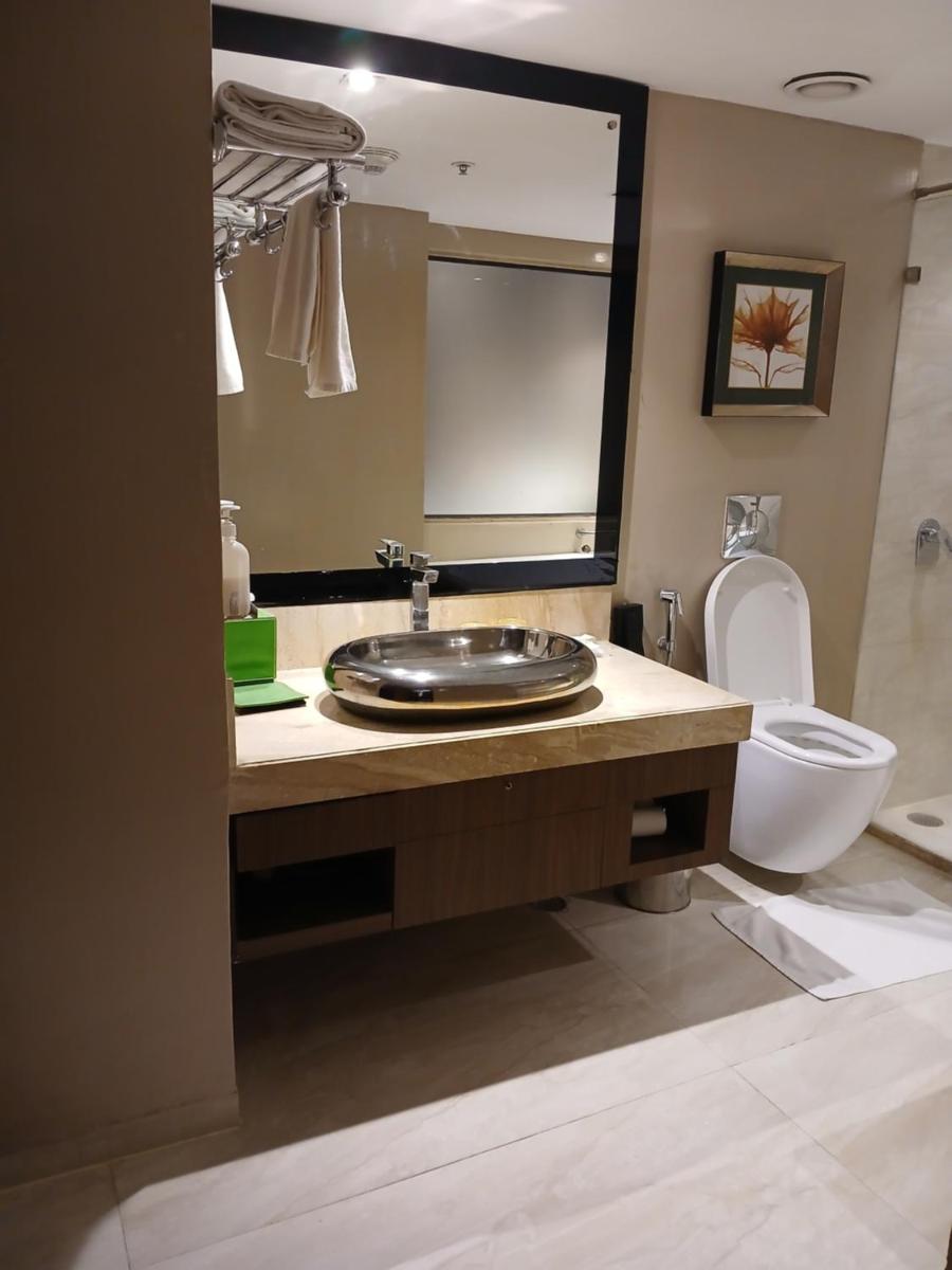 a bathroom with a sink and a toilet and a mirror at Holiday Inn Kolkata Airport by IHG in Kolkata