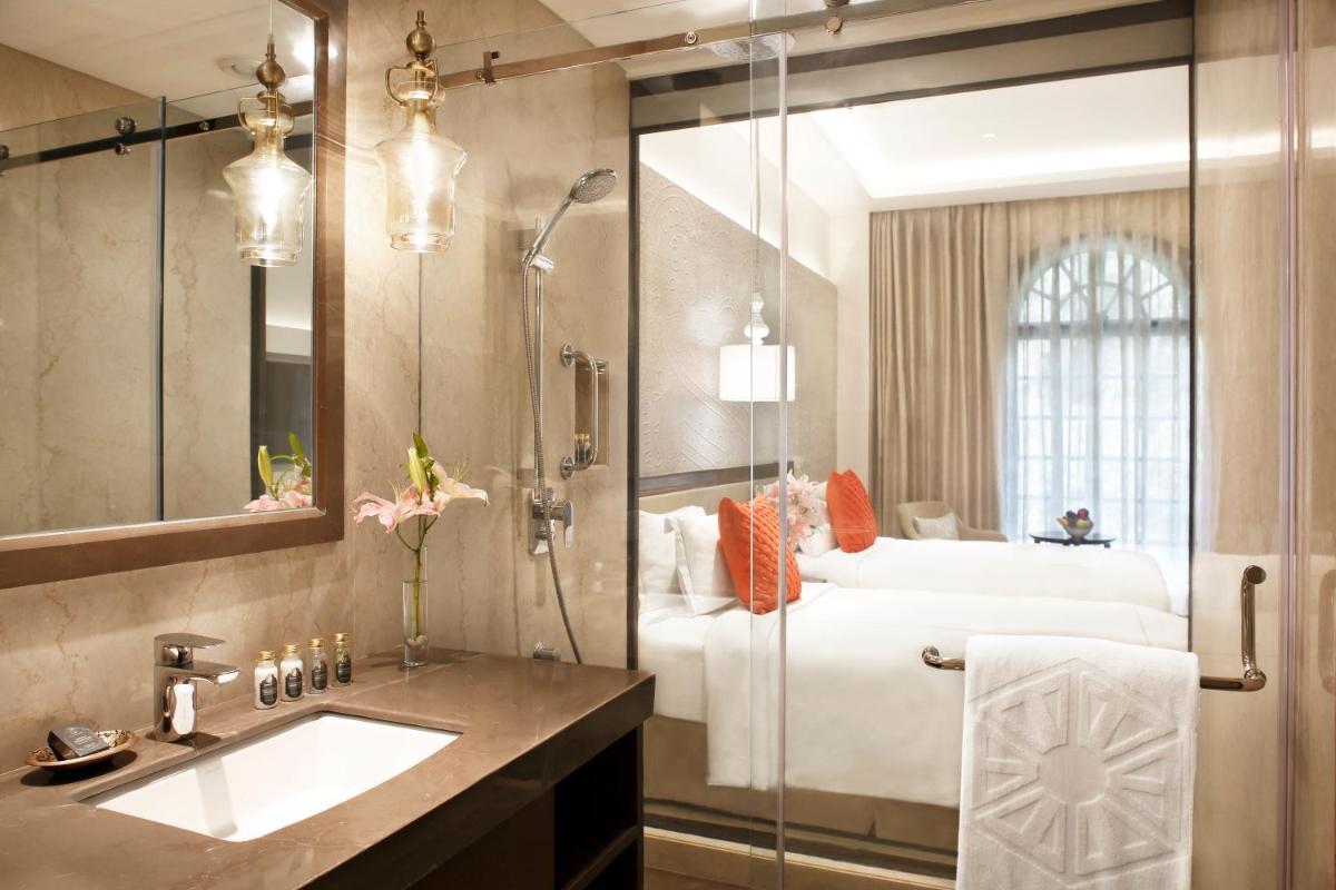 a bathroom with a shower and a sink and a bed at Taj Mahal Lucknow in Lucknow