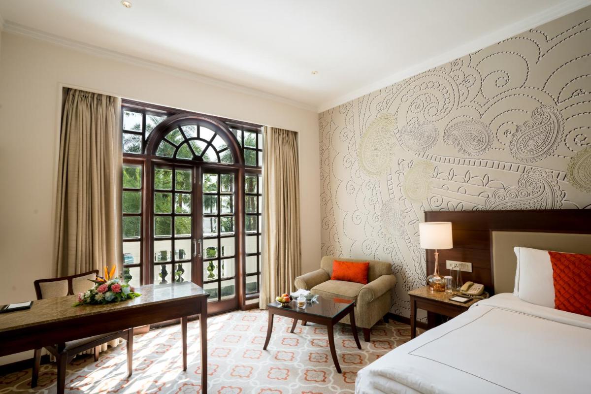 a hotel room with a bed and a desk and a chair at Taj Mahal Lucknow in Lucknow