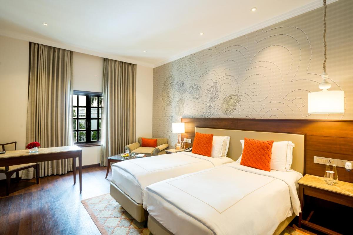 a hotel room with a large bed and a desk at Taj Mahal Lucknow in Lucknow