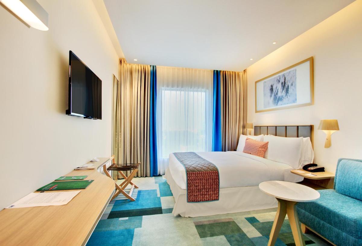 a hotel room with a bed and a blue couch at Holiday Inn Bengaluru Racecourse by IHG in Bengaluru a hotel room with a bed and a blue couch at Holiday Inn Bengaluru Racecourse by IHG in Bengaluru