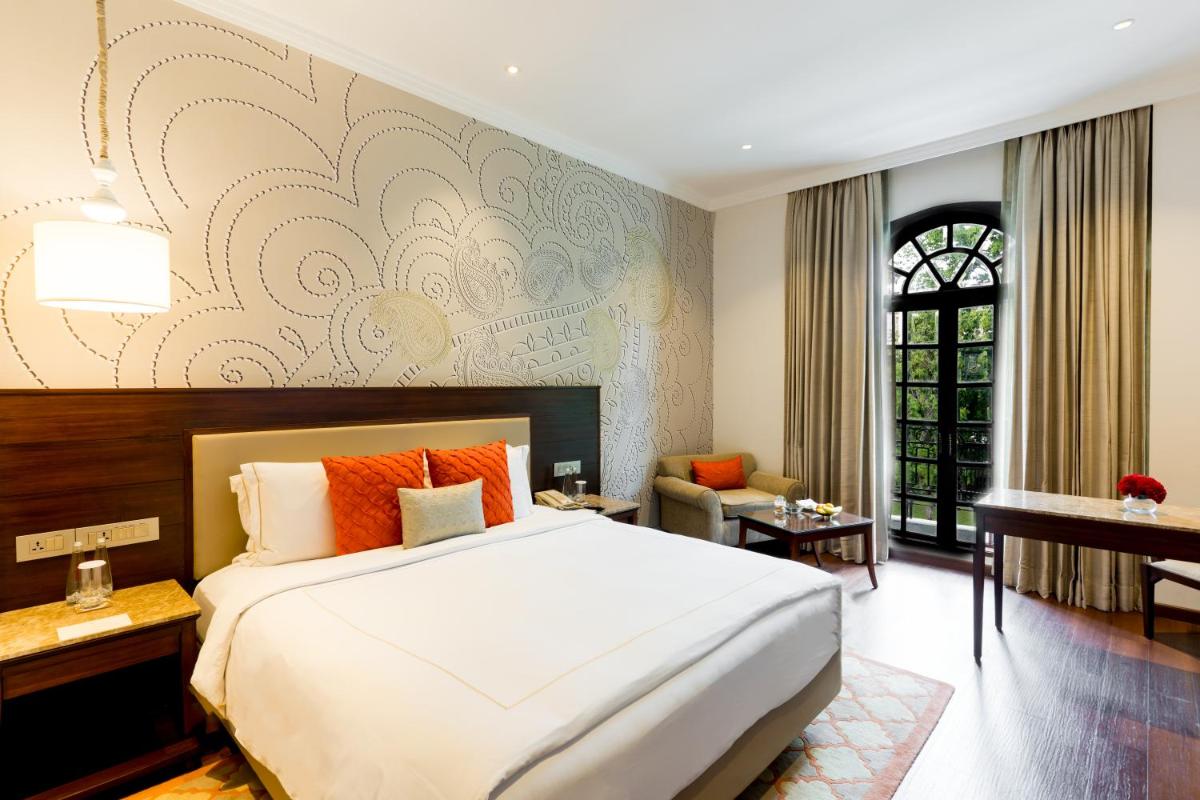 a bedroom with a large bed with orange pillows at Taj Mahal Lucknow in Lucknow