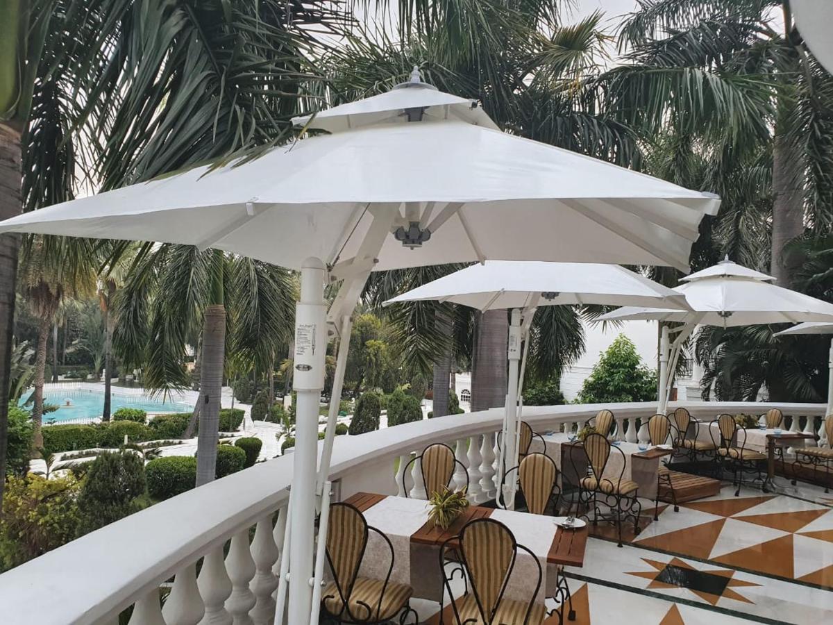 a balcony with tables and chairs and umbrellas at Taj Mahal Lucknow in Lucknow