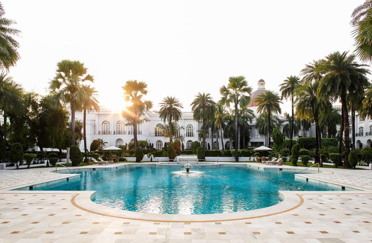 a pool in front of a building with palm trees at Taj Mahal Lucknow in Lucknow