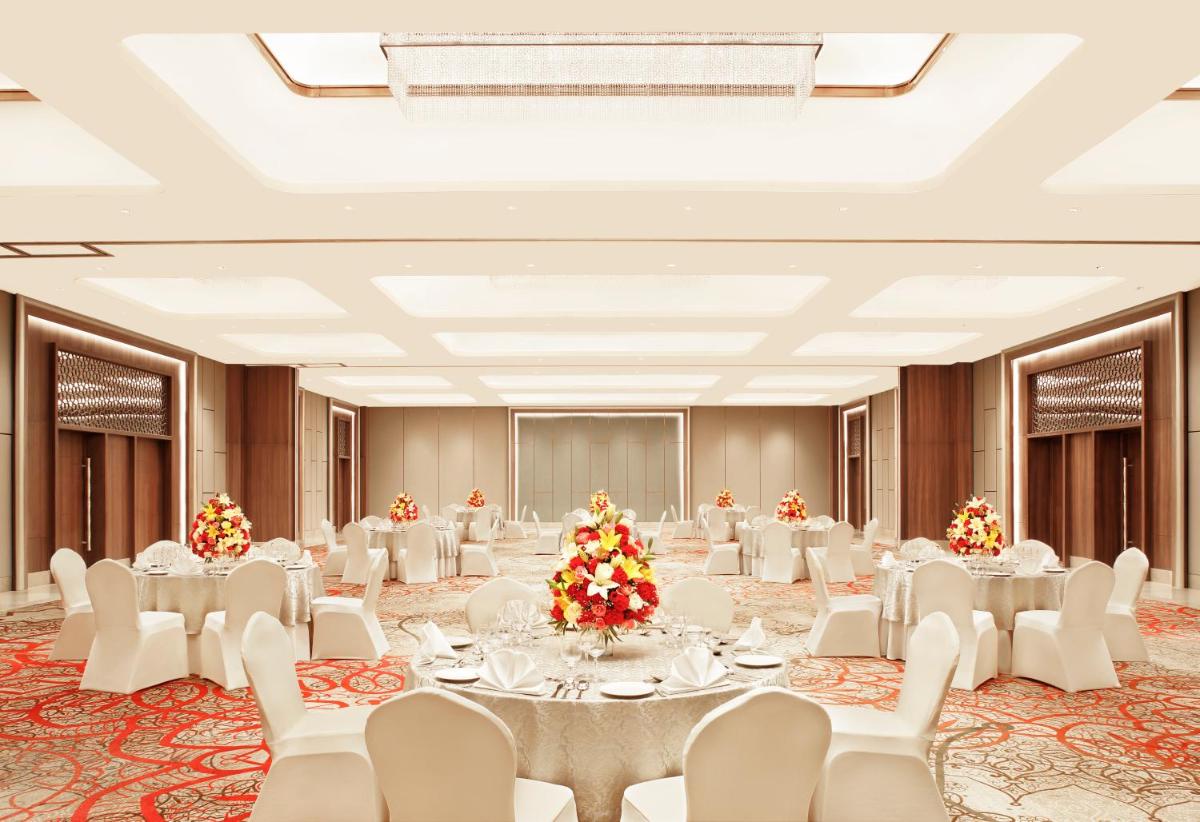 a large banquet hall with white tables and white chairs at Taj Mahal Lucknow in Lucknow
