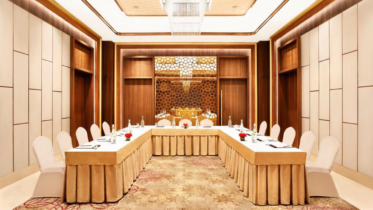 a conference room with a long table with white chairs at Taj Mahal Lucknow in Lucknow