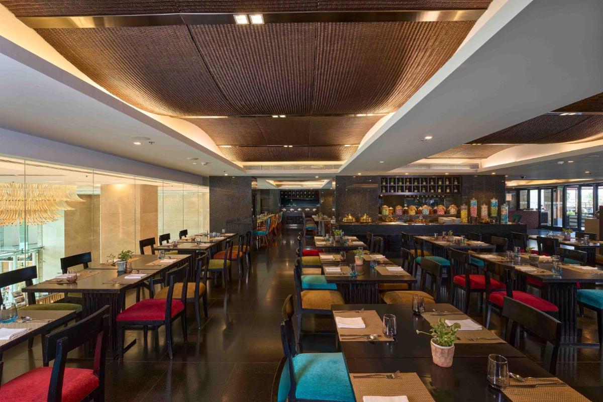 a dining room with tables and chairs and a restaurant at Crowne Plaza Kochi by IHG in Cochin