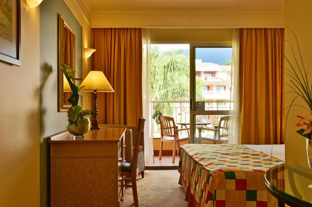 um quarto de hotel com uma cama e uma varanda em Pestana Miramar Garden & Ocean Hotel no Funchal