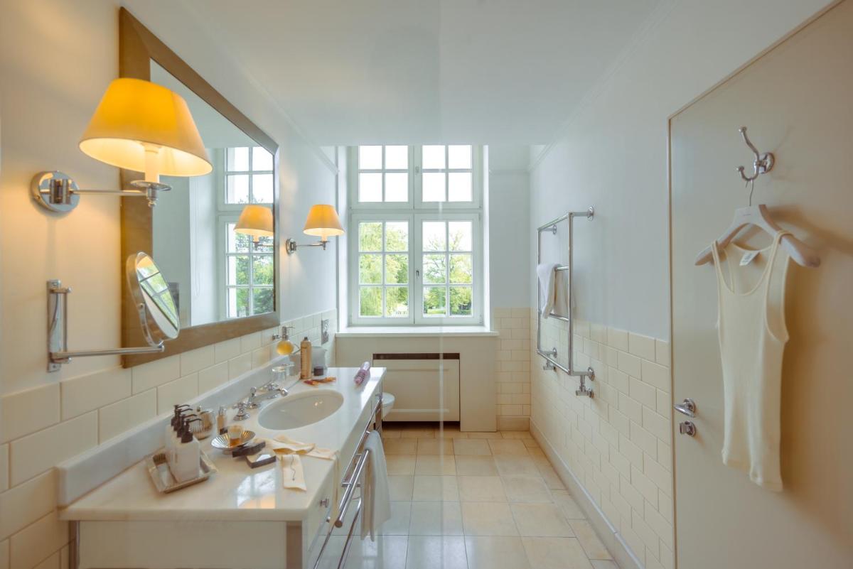 ein Badezimmer mit Waschbecken und Spiegel in der Unterkunft Parkhotel Quellenhof Aachen in Aachen