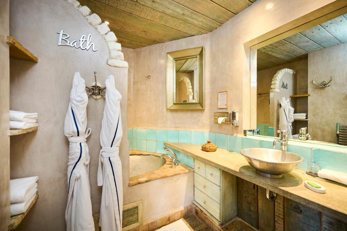 une salle de bains avec lavabo, baignoire et miroir dans l'établissement U Capu Biancu, à Bonifacio