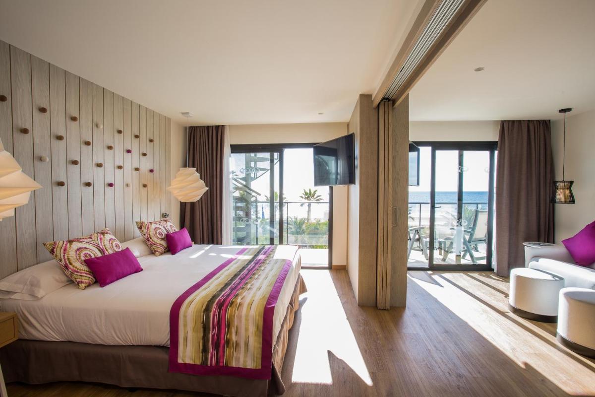 Un dormitorio con una cama grande con almohadas moradas. en Grand Palladium White Island Resort & Spa - All Inclusive, en Playa d'en Bossa