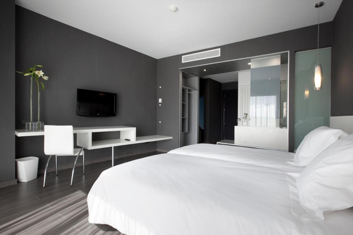 Un dormitorio con una gran cama blanca y un escritorio. en Hotel MasMonzon, en Monzón 50 fotos más
