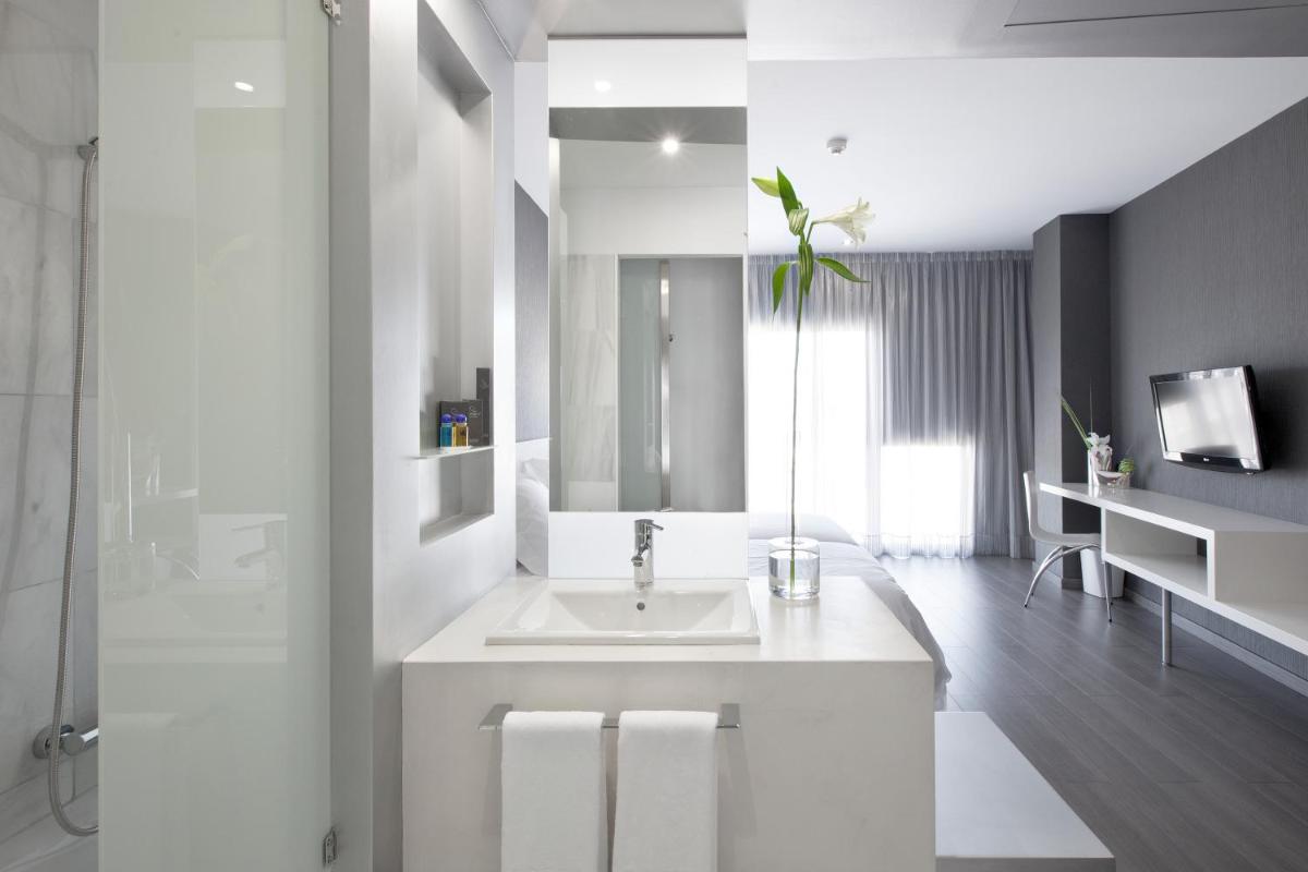 Un baño blanco con lavabo y ducha. en Hotel MasMonzon, en Monzón