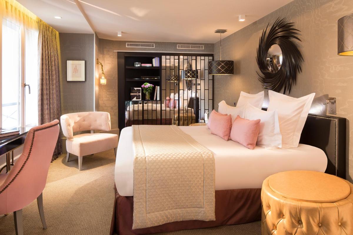 une chambre avec un grand lit avec des oreillers roses dans l'établissement Hôtel Baume, à Paris