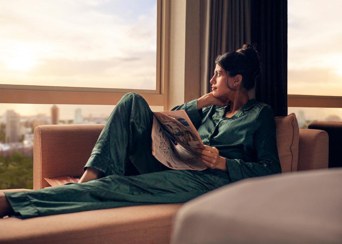 a woman sitting on a couch reading a book at Four Seasons Hotel Mumbai in Mumbai
