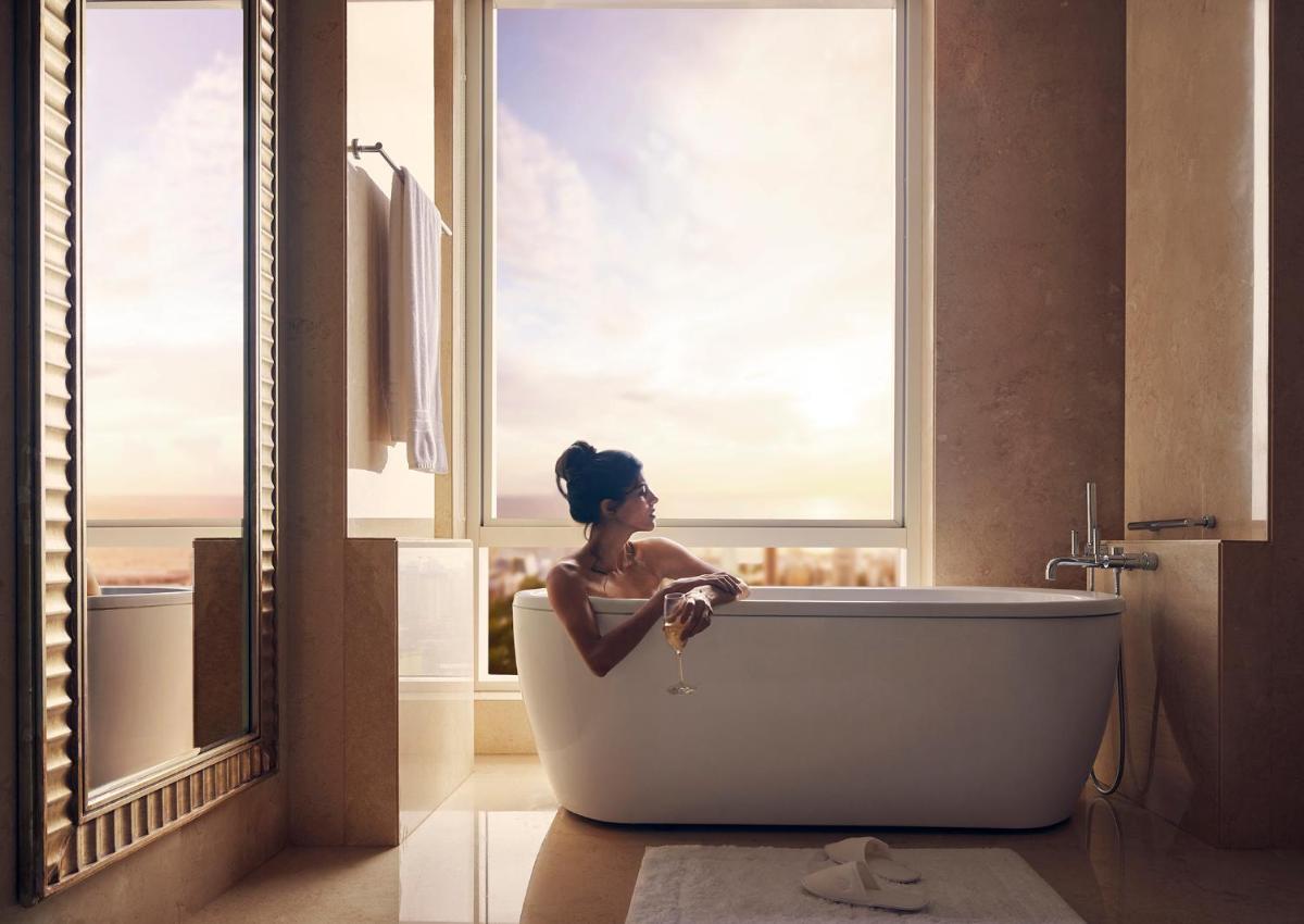 a woman sitting in a bath tub in a bathroom at Four Seasons Hotel Mumbai in Mumbai
