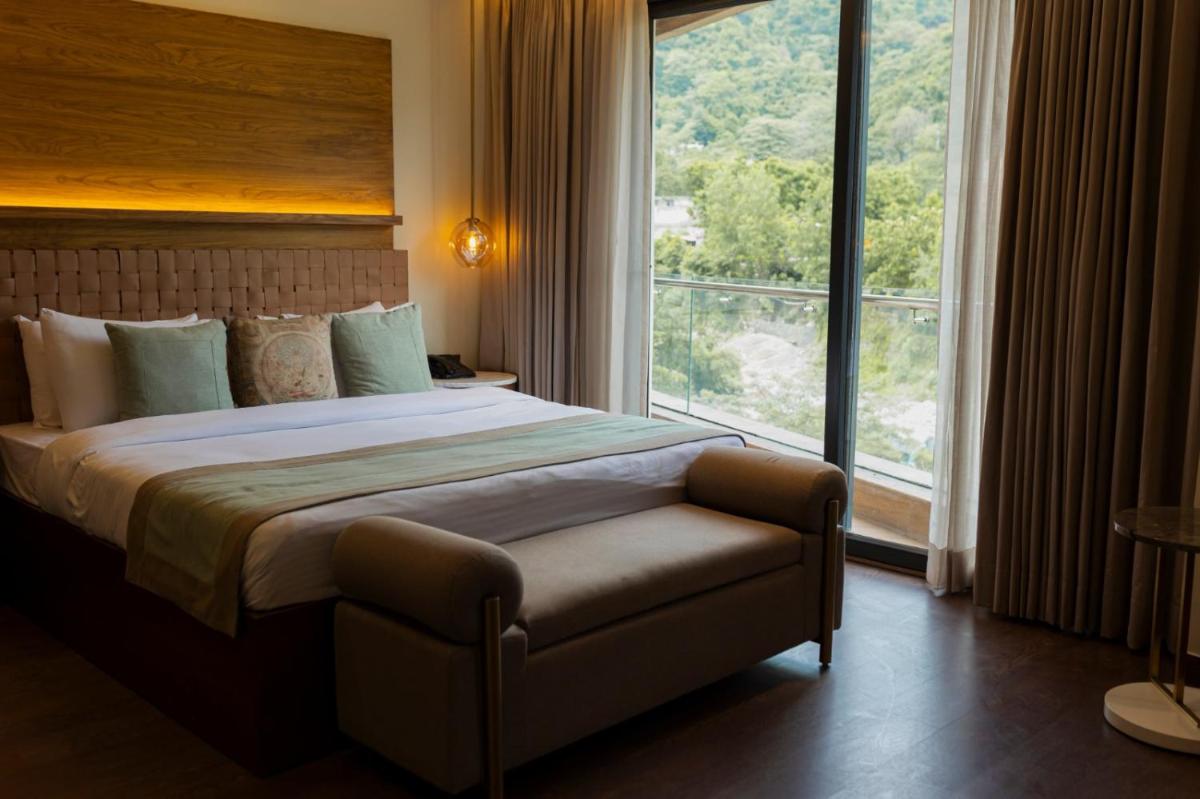 a bedroom with a large bed and a large window at Antalya By Divine Ganga Cottage in Rishīkesh