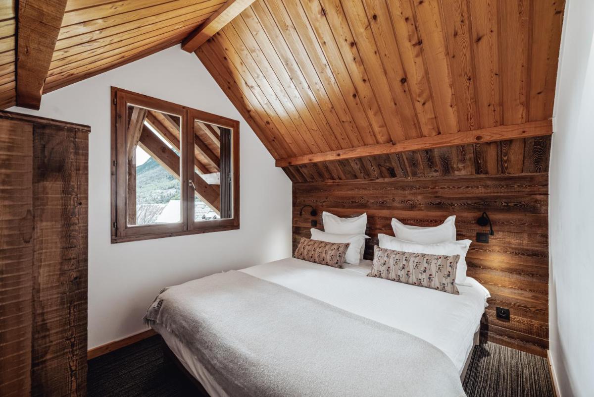 un lit dans une chambre avec un plafond en bois dans l'établissement Alliey & Spa Piscine Appart-hôtel Serre chevalier, au Monêtier-les-Bains